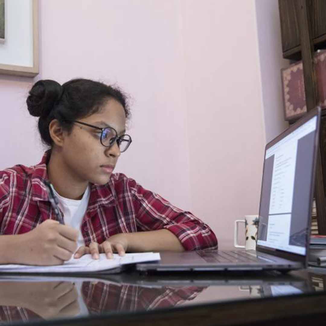 Young women studying with a laptop. Photo: Mawa/Unicef